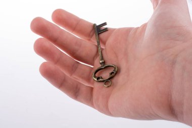 Beyaz arka planda eski moda metal bir anahtar tutan el.