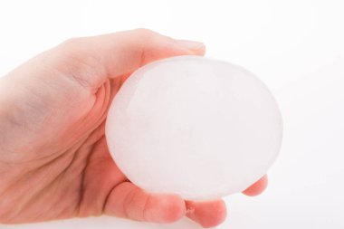 Beyaz arka planda bir buz topu tutan el.