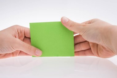 Beyaz zemin üzerinde açık yeşil dikdörtgen bir kağıt tutan el.