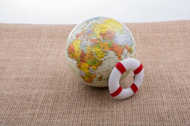 Tuvalin arka planına yerleştirilmiş bir kürenin yanında can yelekleri