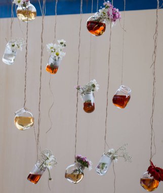 İplere asılı çiçekli bitkisel çay şişeleri