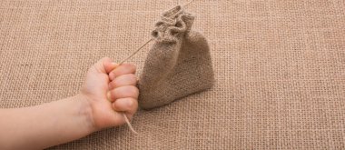 Çarşaftan yapılmış boş bir çuvalı tutan el.