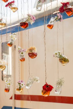 İplere asılı çiçekli bitkisel çay şişeleri