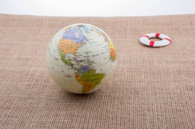 Tuvalin arka planına yerleştirilmiş bir kürenin yanında can yelekleri