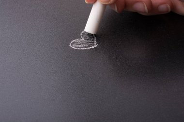 Elinde beyaz tebeşir ve siyah tahta var.