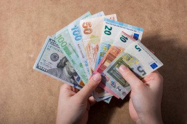 El ele tutuşan Amerikan doları banknotları ahşap arka planda izole edilmiş.