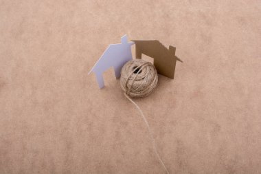 Kağıttan kesilmiş ev şekli ve iplik kahverengi arkaplan makarası