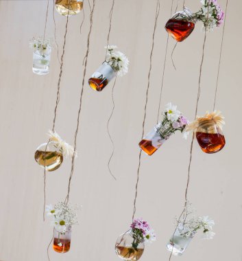 İplere asılı çiçekli bitkisel çay şişeleri