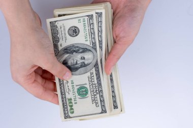 İnsan eli, Amerikan doları banknotunu beyaza izole edilmiş olarak tutuyor.