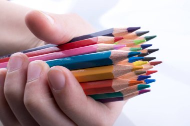 Beyaz arkaplanda el ele tutuşan renkli kalemler