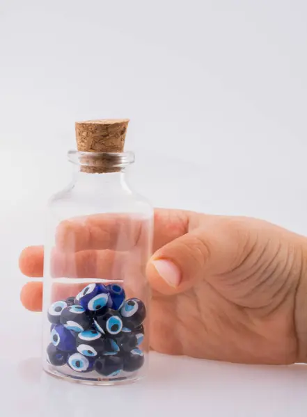 stock image Little  glass bottle  with blue evil eye bead in hand