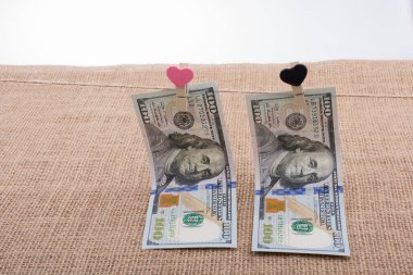 100 dolarlık banknotlar ve bir kalp klipsi.