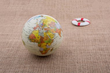 Tuvalin arka planına yerleştirilmiş bir kürenin yanında can yelekleri