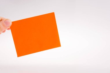 Beyaz bir arka plan üzerinde turuncu renkli dikdörtgen kağıt tutan el