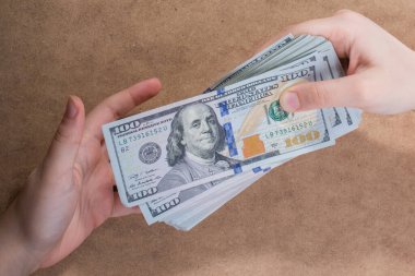El ele tutuşan Amerikan doları banknotları ahşap arka planda izole edilmiş.