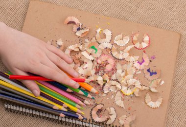 Kalem talaşı olan bir defterin üzerinde Renkli Kalem 'i tutarken