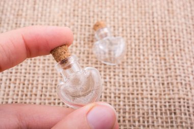 Kalp şeklinde cam şişeler el ele tutulur.