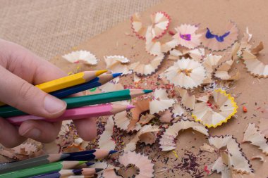 Bir defter kalem talaş ile üzerinde renkli kalemler tutan el