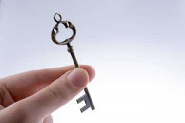 Beyaz arka planda eski moda metal bir anahtar tutan el.