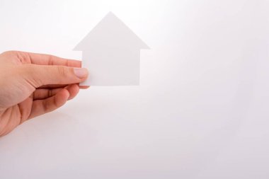 Beyaz bir arka plan üzerinde bir kağıt ev tutan el