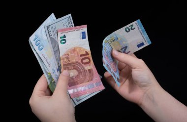 El ele tutuşan Amerikan doları banknotları siyah arka planda izole edilmiş.