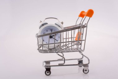 Beyaz zemin üzerinde bir alışveriş arabası çalar saat