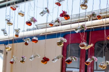 İplere asılı çiçekli bitkisel çay şişeleri