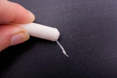 Elinde beyaz tebeşir ve siyah tahta var.