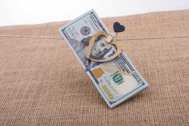 100 dolarlık banknotlar ve bir kalp klipsi.