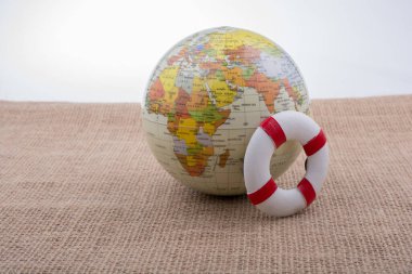 Tuvalin arka planına yerleştirilmiş bir kürenin yanında can yelekleri