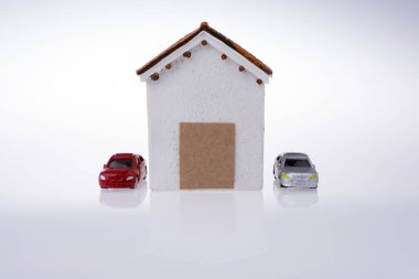 Küçük modeli ev ve beyaz zemin üzerine iki araba