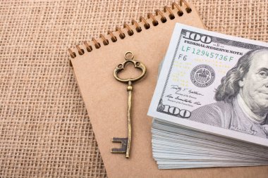 Geriye dönük anahtar ve bir deste Amerikan doları bir deftere konmuş.