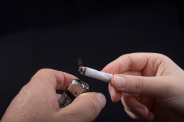 El siyah arka planda bir sigara yakıyor.