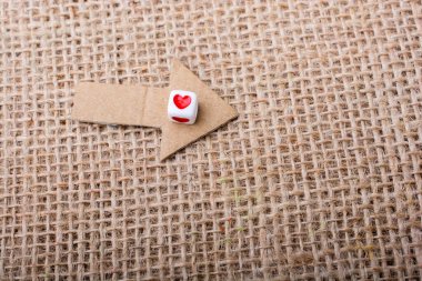 Love cubes on arrow cut out of brown paper on canvas clipart