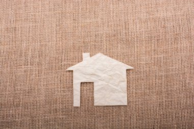 Tuvalin arka planında kağıttan yapılmış küçük bir ev şekli.