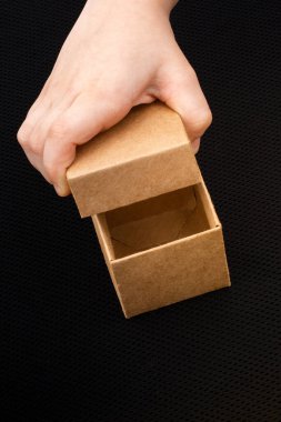 Siyah arka planda kahverengi bir karton kutu açılıyor.