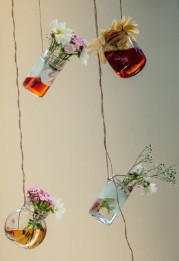 İplere asılı çiçekli bitkisel çay şişeleri