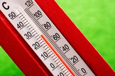 Yeşil arka plan üzerinde kırmızı plastik termometre