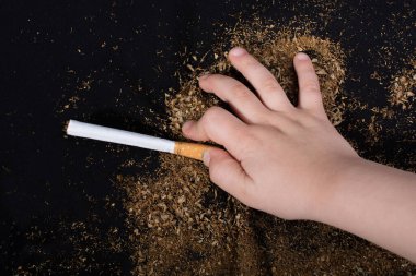 El siyah arka planda bir sigara tutuyor.