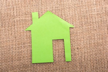 Tuvalin arka planında kağıttan yapılmış küçük bir ev şekli.