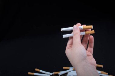 Siyah arka planda sigara tutan bir el var.