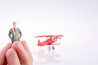 Beyaz bir arka plan üzerinde kırmızı bir insan figürü uçakla tutan el