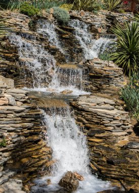 Küçük bir göle dökülen kayalık bir şelale.