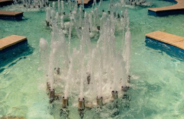 Çeşmeler parktaki bir havuzda köpüklü su fışkırtıyor.