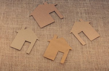 Tuvalin arka planında kağıttan yapılmış küçük bir ev şekli.