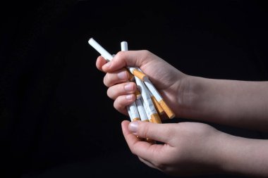 El, siyah arka planda bir paket sigara dağıtıyor.