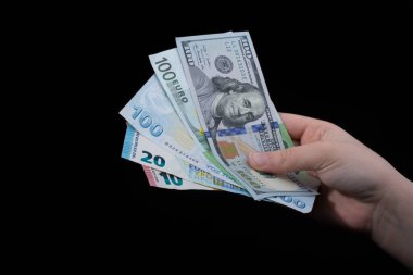 El ele tutuşan Amerikan doları banknotları siyah arka planda izole edilmiş.