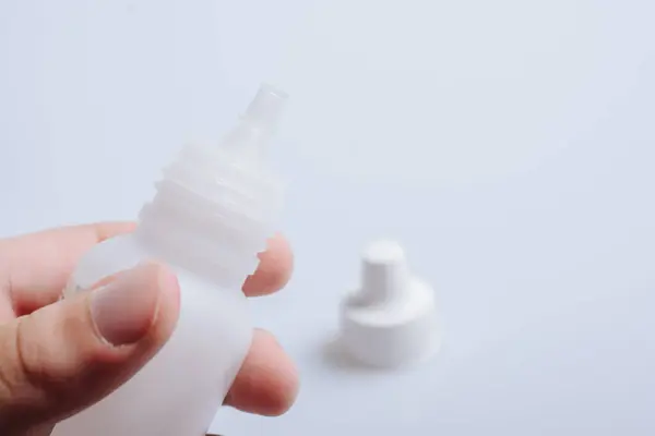 stock image White empty  dropper bottle in hand on a white background