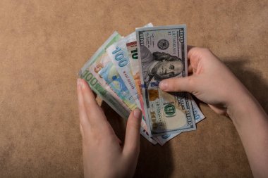 El ele tutuşan Amerikan doları banknotları ahşap arka planda izole edilmiş.