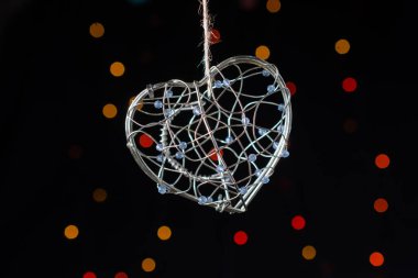 Heart shaped metal cage on a bokeh light background clipart